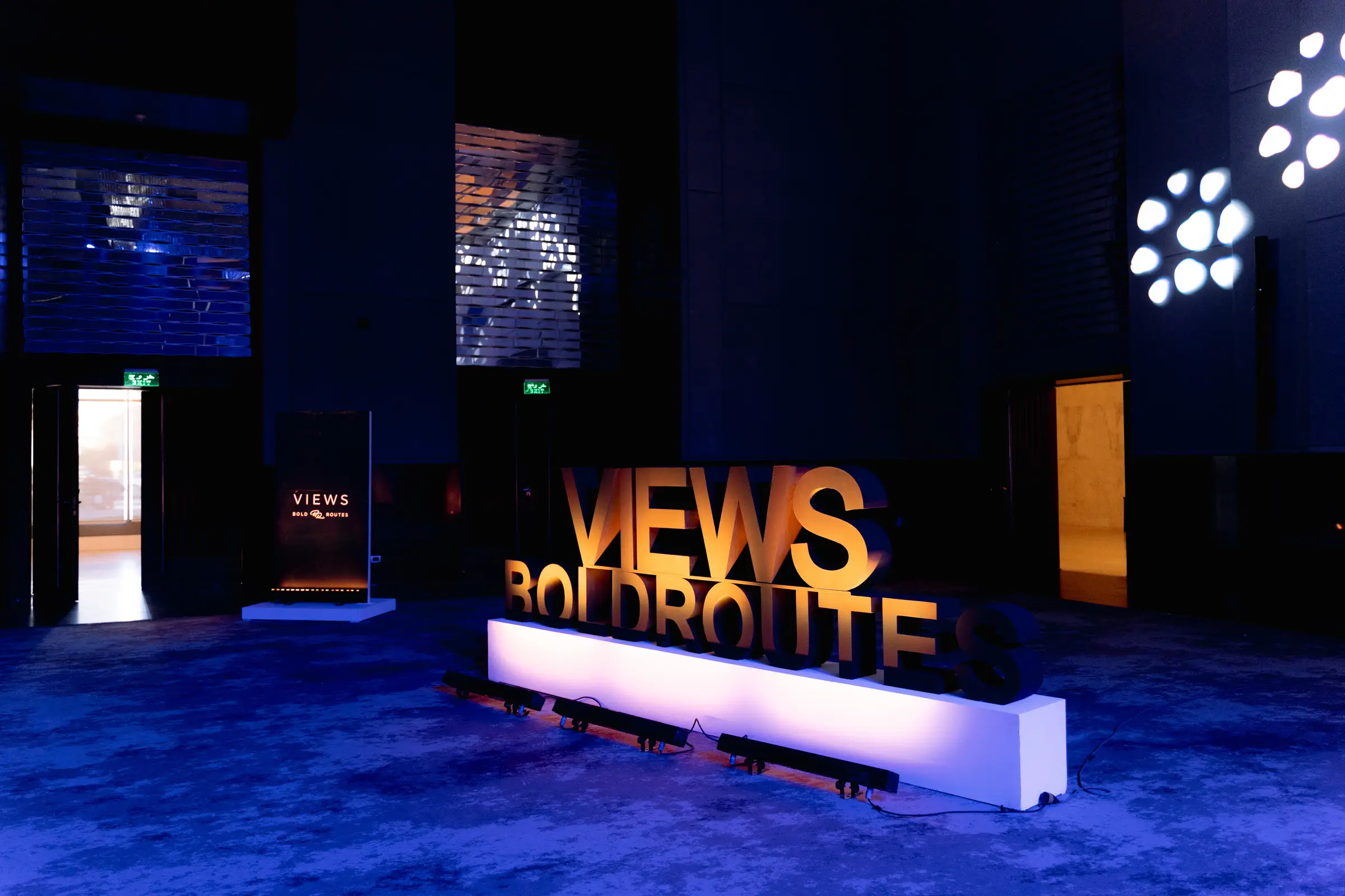 Sculptural Bold Routes installation with warm spotlights and deep blue architectural lighting